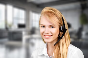 Young friendly female operator with headsets in a call centre.