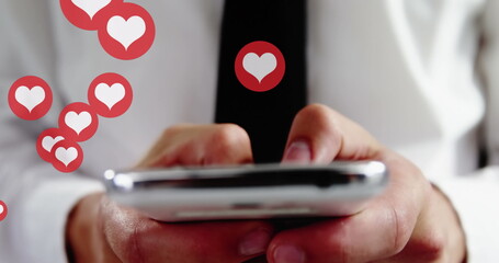 Image of hearts over hands of biracial man using smartphone