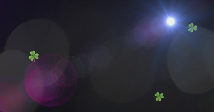 Image of light spots and clovers over black background - Powered by Adobe