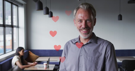 Caucasian male manager, wearing grey shirt and red tie, smiling in a cafe