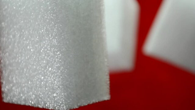 white rectangular pieces of synthetic sponge foam. supple material, soft padding in the form of blocks with a red background