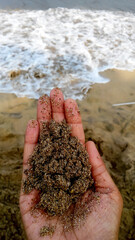 a woman holding beach sand against a beach background