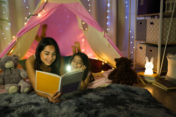 Heartwarming moment: a hispanic mother reading a bedtime story to her daughter in a cozy bedroom...