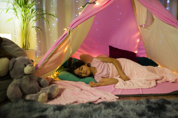 Young latina girl peacefully sleeping in her cozy bedroom with a charming tent and glowing star...