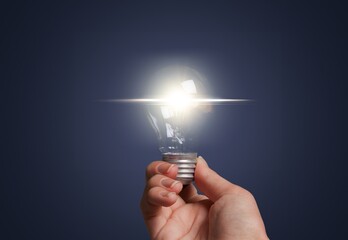 Business person holding bright light bulb.