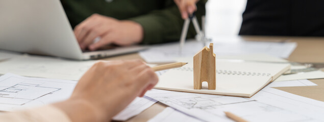 Wooden block was placed on table with blueprint and architectural document scatter around while...