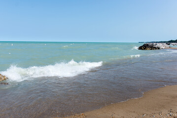Beach near Lake Michigan. Rough waves. A pile of large stones near the lake and the beach.