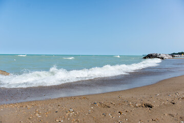 Beach near Lake Michigan. Rough waves. A pile of large stones near the lake and the beach.