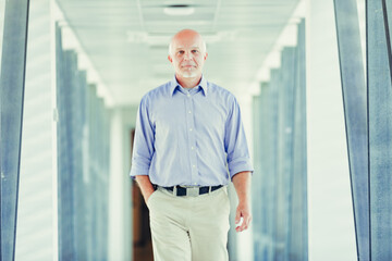 Senior man walks confidently in modern corridor
