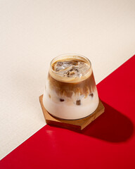 a cup of cold latte coffee on a red and white background