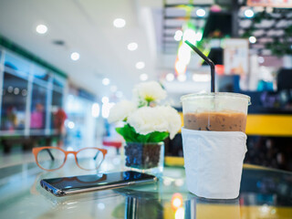 Iced coffee on glass table blurred coffee shop background