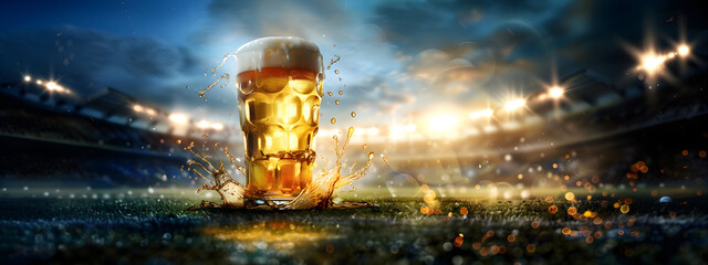 Glass with lager foamy beer on grass at soccer  stadium. Game and drink, sports fan. Watch football or rugby match with friends. World championship cup. Super Bowl. Banner with copy space
