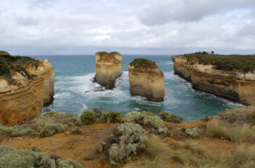Rock formations, sea, plants and overcast sky at Loch Ard Gorge on the Great Ocean Road in Victoria, Australia