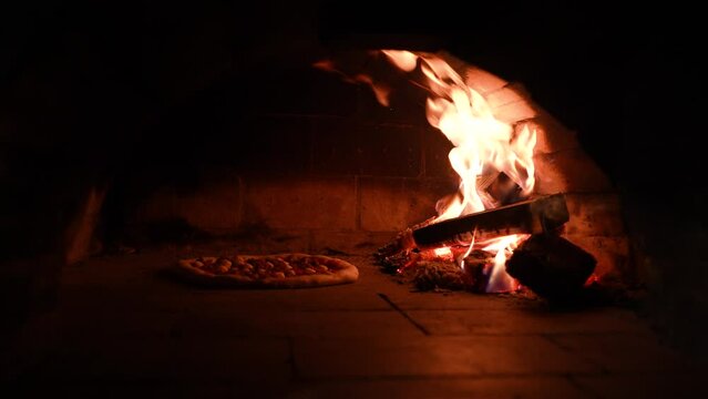 Static shot of Traditional way baked wood fired oven with Italian pizza.