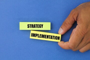 hand holding colored paper with the word Strategy Implementation