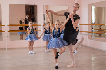 Children's ballet school. Caucasian woman teaching ballet to little girls. 