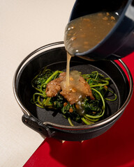 sautéed kale served on a hotplate with pieces of meat and garlic