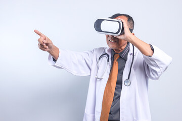 Senior Male Doctor Pointing To Leftside Wearing Virtual Reality Glasses Isolated On White Background