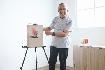 Potrait Of Happy Senior Asian Man Wear Glasses Pointing At His Painting