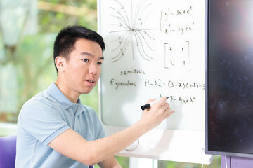 College student gesturing while writing on a whiteboard in a classroom discussion