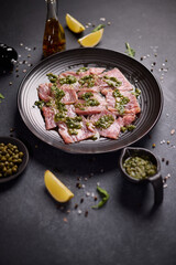 tuna carpaccio - slices of fresh raw tuna fillet on black ceramic plate