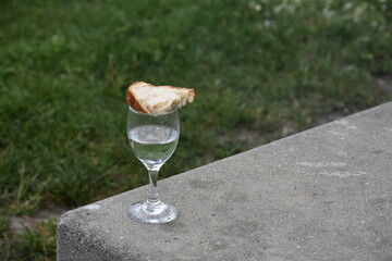 a glass of vodka and a piece of bread on it