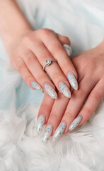 Elegant Hands Featuring Sparkling Ring and Blue Floral Manicure on Delicate White Fabric