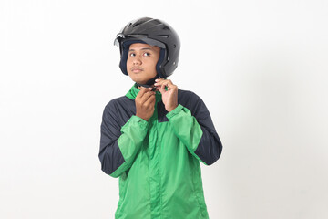 Portrait of Asian online taxi driver wearing green jacket and helmet demonstrating how to wear helmet correctly. Isolated image on white background