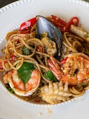 a photography of a bowl of pasta with shrimp and other food.
