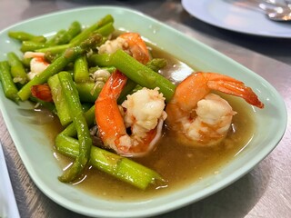 a photography of a plate of shrimp and asparagus with gravy.