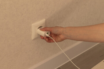 Hand plugging in or out an electric cord into a socket