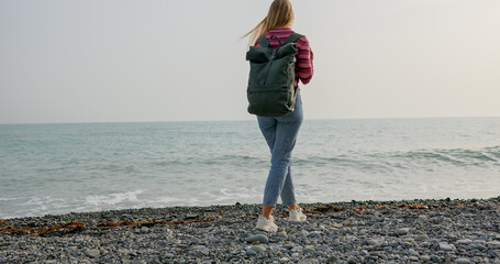 Young woman traveler goes walking along the sea