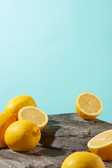 Some fresh yellow lemon scattered lay on the rock over light blue background, photo for advertise product has natural origin, blank space for adding text