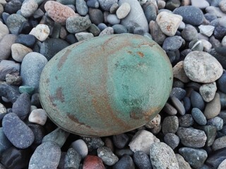 Big green sea pebble stone or rock in oval shape as frame on beach. Pebble stone natural abstract texture or background oval frame. Pebble stone oval frame on seacoast. Pebble oval in gravel frame