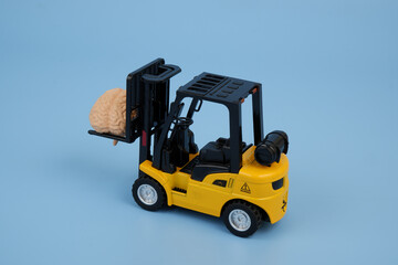 Forklift truck carrying human brain on blue background. Smart logistics concept.
