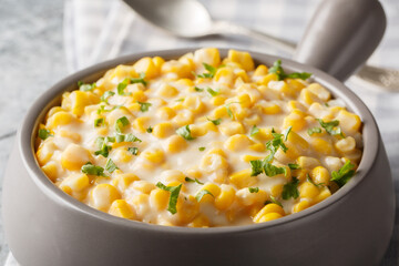 Sweet corn with rich cream, butter, parmesan cheese closeup on the bowl on the table. Horizontal