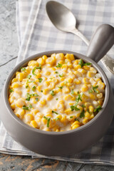 Creamed Corn is a classic side dish consists of tender corn kernels bathed in a rich creamy sauce closeup on the bowl on the table. Vertical
