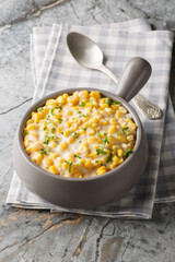 Creamed corn or cream-style sweet corn is a type of creamed vegetable dish closeup on the bowl on the table. Vertical