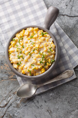 Creamed Corn is a classic side dish consists of tender corn kernels bathed in a rich creamy sauce closeup on the bowl on the table. Vertical top view from above