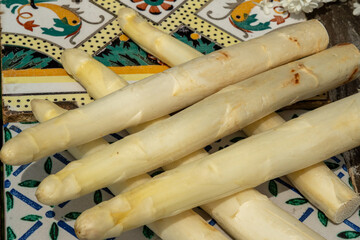 Seasonal cuisine: fresh asparagus stacked on colorful tiles