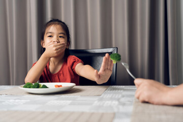 Little cute kid girl refusing to eat healthy vegetables. Children do not like to eat vegetables.