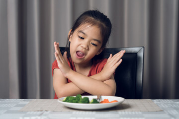 Little cute kid girl refusing to eat healthy vegetables. Children do not like to eat vegetables.