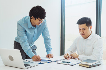 Two businessmen are analyzing company earnings figures at their desks.