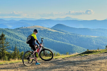 Cyclist man riding electric bike outdoors on sunny day. Male tourist resting on hill, enjoying...