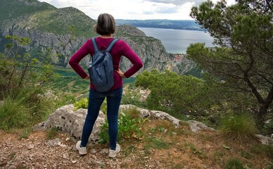 Rear view of senior woman hiking on the mountain with beautiful view on Omis and Adriatic sea
