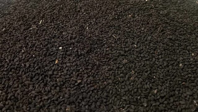 Black cumin seeds or black caraway seeds rotating full frame background, side view looped spinning, close up, herbs and spices