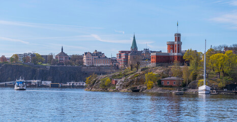 Small harbor ferry Djurgården passing the castle on the island Kastellholmen, the district Södermalm in the background, a sunny summer morning in Stockholm