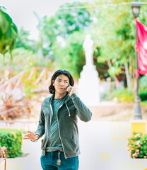 Young man gesturing and talking on the phone in a park. Latin guy talking on cell phone outdoors
