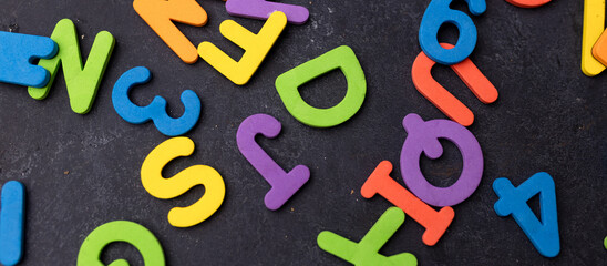 Top view of letters of the English alphabet scattered on a black background. The concept of the...