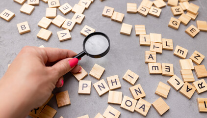 Square letter tiles with magnifying glass against blue background. Search for words and information...